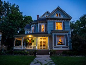 Night time view of the exterior of Victorian two story home with lights on