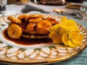 Gourmet breakfast with pancakes, bananas and syrup on colorful china plate