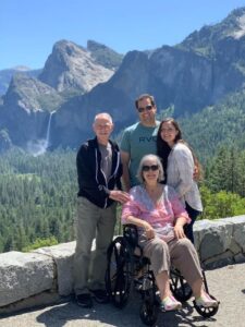 Young couple posing in mountains with older couple with the woman in a wheelchair