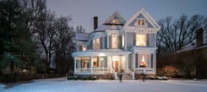 snow covered blue two story Victorian home