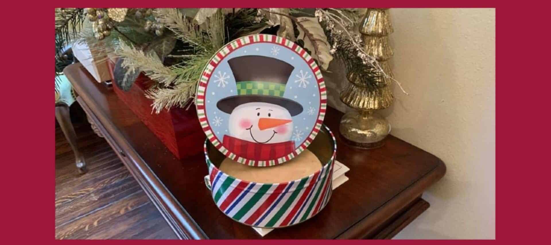 snowman tin with peanut butter fudge in front of Christmas decor