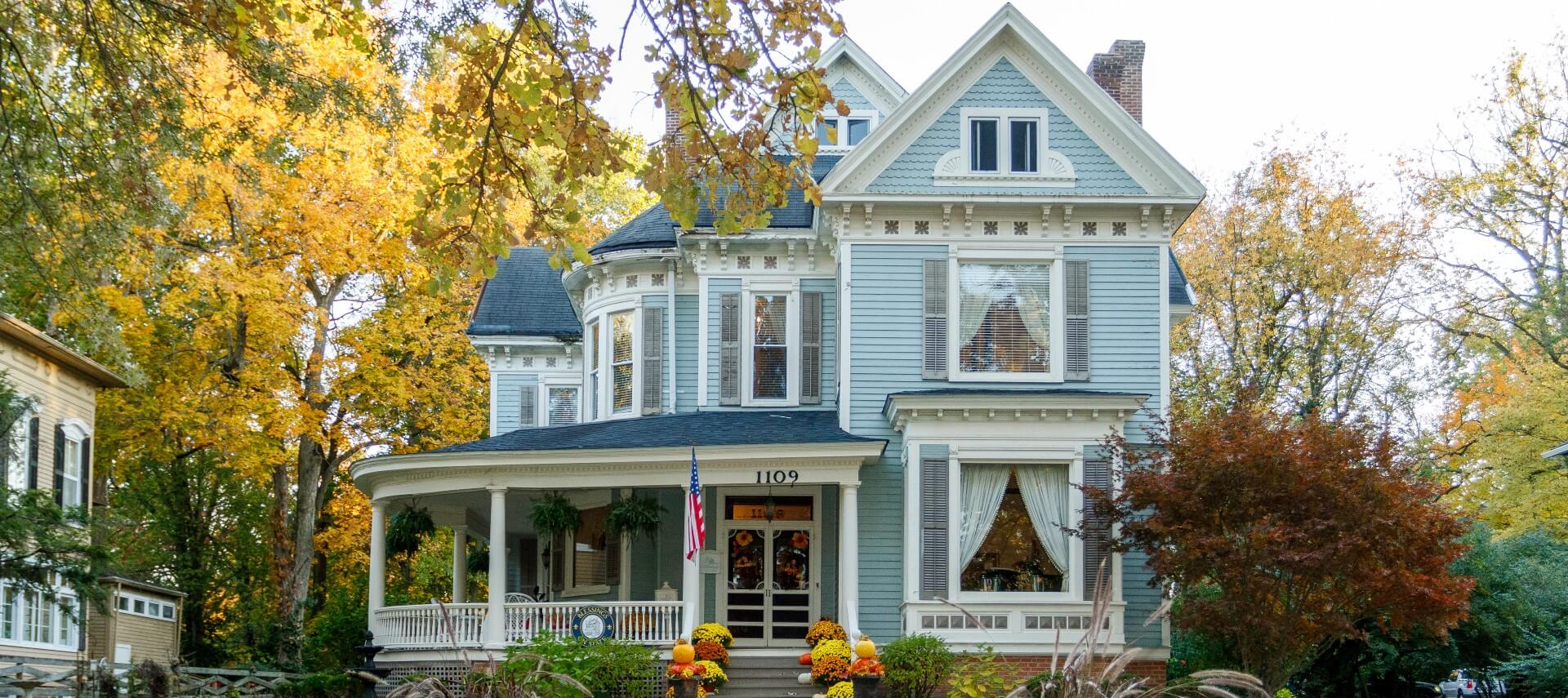 Blue Victorian home with fall pumpkin and mum decor