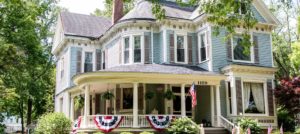 Patriotic bunting hangs on front porch of blue Victorian home