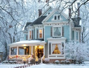 Christmas lights shine around a snowy two-story Victorian home