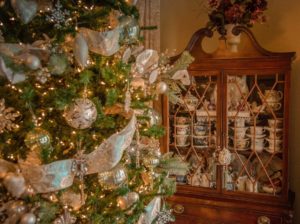 Decorated Christmas tree in front of antique cabinet