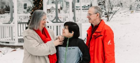 grandparents with grandson in snowy yard