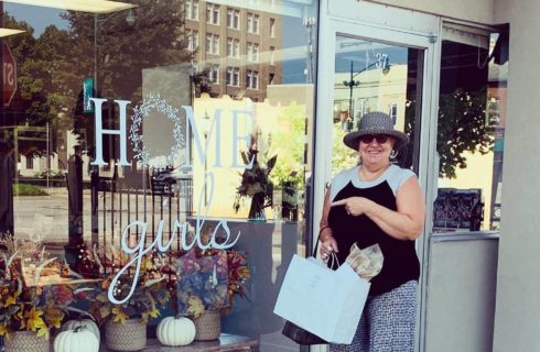 Woman standing with a shopping bag in front of the Home Girls store