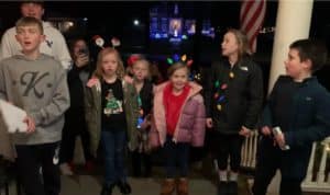 Young Christmas carolers on the front porch