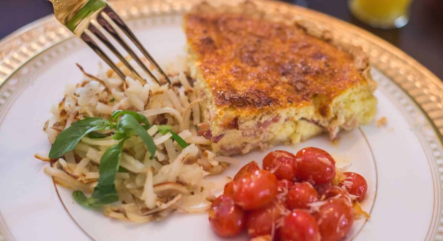 Close up view of breakfast dish with quiche, potatoes, and tomatoes