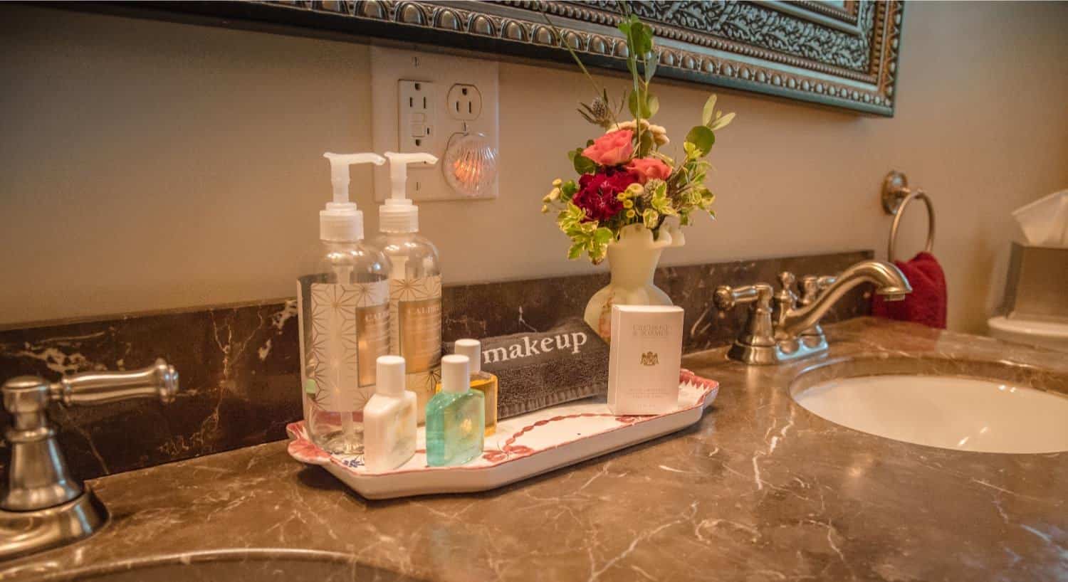 Bathroom vanity with a tray including soaps and lotions and small bouquet of fresh flowers