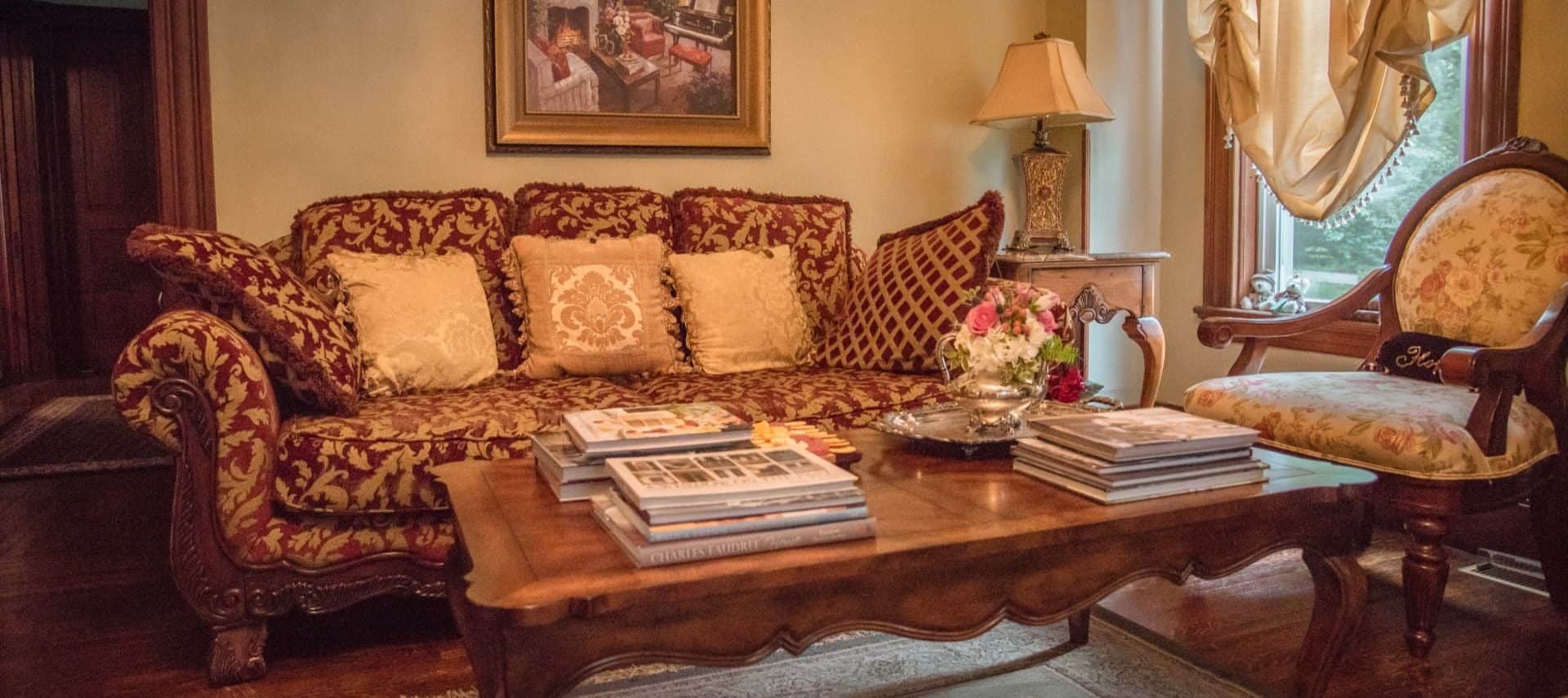 Victorian sofa and chair with upholstered cushions and wooden frame and wooden coffee table with books