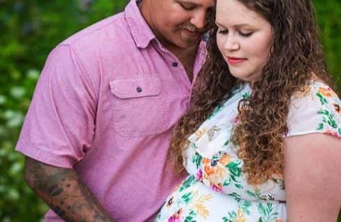 Man with pink shirt hugging pregnant lady with floral shirt